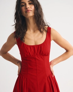 Detail of red sleeveless midi dress showing U-neckline and pleated waist structure