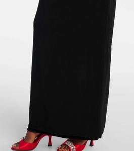 Détail d'une robe longue noire ajustée associée à d'élégants talons hauts rouges