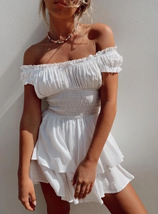 Detail of white Swiss dot dress featuring off-shoulder ruffle neckline and smocked waist