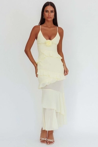 Detail of light yellow maxi dress featuring tiered ruffles and 3D rose accent on V-neckline