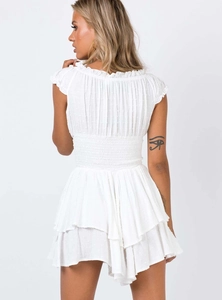 Detail view of Swiss dot fabric and smocked waist on a white summer mini dress