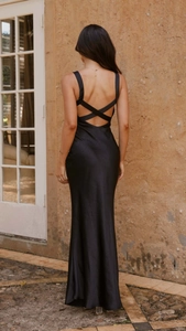Detail of the open back design with thin crossover straps on a black satin evening gown