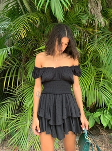 Detail of black off-shoulder mini dress with tiered ruffle skirt and smocked waistline