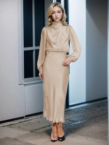 Dettaglio di elegante completo due pezzi in raso champagne con maniche lunghe e gonna