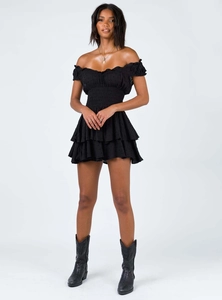 Detail of black off-shoulder mini dress featuring smocked waist and swiss dot texture