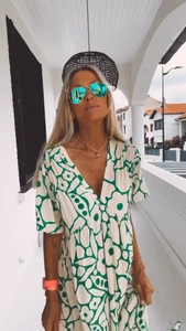 Detail of V-neck summer maxi dress featuring green floral print on white fabric