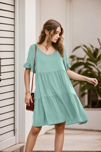 Detail of mint green V-neck dress featuring tiered ruffle hem and flutter short sleeves