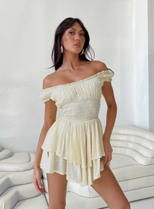 Detail of light yellow off-shoulder dress featuring dot texture and layered skirt design