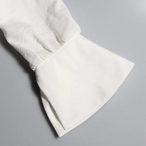 Detail of white long sleeve dress showing flared bell cuff and textured chiffon fabric