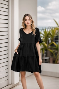 Detail view of black V-neck tiered babydoll dress with ruffle sleeves and side pockets