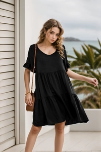 Detail of V-neck tiered mini dress in black featuring ruffled sleeves and flowing layers