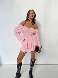 Detail of pink off-shoulder mini dress featuring smocked waist and polka dot texture