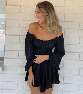 Detail of black off-shoulder dress featuring Swiss Dot fabric and tiered ruffle hemline