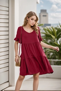 Detailed view of the wine red V-neck tiered mini dress with ruffle sleeves on a terrace