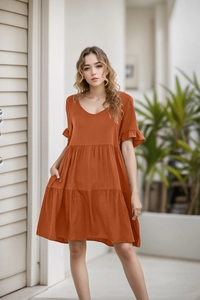 Close-up of rust red tiered dress featuring a V-neckline and delicate ruffle sleeves
