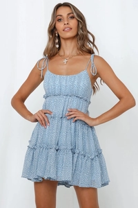 Détail de robe fleurie bleu clair montrant l'ourlet à volants et fines bretelles à nouer