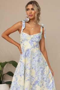 Details der verstellbaren Schleifenträger und des Blumenmusters am eng anliegenden Midikleid