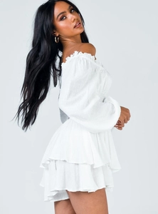Detail of white off-shoulder dress featuring ruffled edges and textured Swiss dot fabric