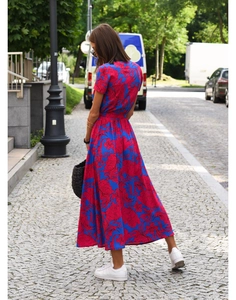 Rear view of a flowy royal blue maxi dress with vibrant pink floral prints on a street