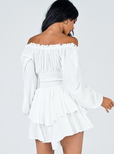 Detail of white off-shoulder mini dress featuring embroidery and ruffled hemline