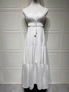 Detailed close-up of white ruffled neckline with delicate tassels and smocked high waist