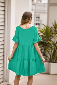 Detail of emerald green tiered summer dress with ruffled sleeves and lightweight fabric
