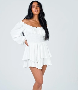 Detail of the elastic shirred bodice and ruffled hem on a white off-shoulder mini dress