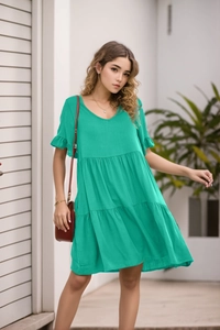 Detail of summer bright green V-neck dress with ruffle sleeves and tiered skirt fabric
