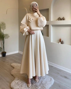 Detalle de flores aplicadas y mangas abullonadas en el elegante conjunto de vestido beige