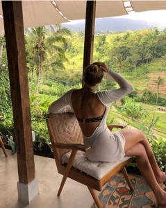 Détail de la robe de plage en maille blanche avec dos nu et manches longues ajourées