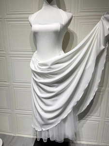 Detail of white halter neck satin gown showing glossy fabric and layered tulle skirt