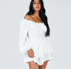 Detail of the white off-shoulder romper with a smocked waist and ruffled hemline