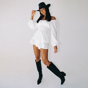 Detail of white off-shoulder romper with smocked waist and tiered ruffle hem