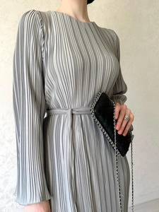 Detail view of grey pleated dress showing vertical texture and waist belt design