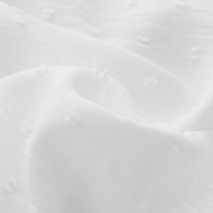 Macro shot of white Swiss dot chiffon fabric showing delicate texture and ruffled details
