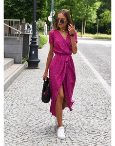 Detail of V-neck fuchsia dress with orange polka dots and waist tie in outdoor lighting