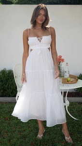 Detail of white tiered maxi dress featuring side cut-outs and bohemian lace-up neckline