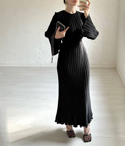 Detail of pleated black maxi dress showing fine vertical textures and elegant waist cut