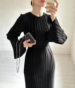 Detail of elegant black pleated midi dress with flared sleeves and satin luster finish