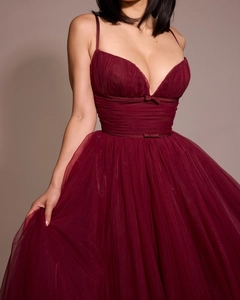 Close-up of burgundy evening dress featuring pleated bodice with delicate bow accents