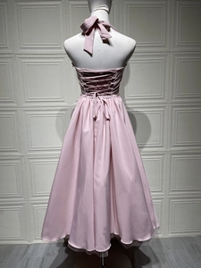 Lace-up back detail of a light pink halter evening dress with pleated elastic waist