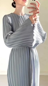 Detail of elegant pleated fabric on a light blue round neck dress with flared sleeves