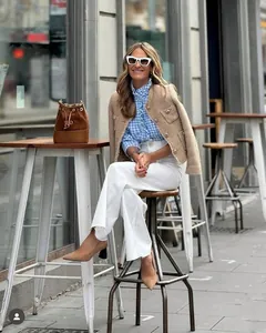 Street style view of a camel tweed short jacket with metallic buttons and white trousers