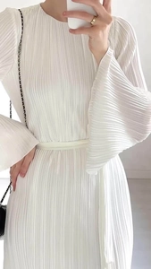 Close-up of elegant pleated white dress featuring flared sleeves and fine fabric texture