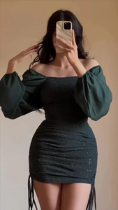 Detail of dark green ruched mini dress with silver glitter and elegant puff sleeves
