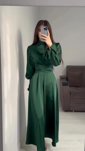 Détails d'une robe en satin vert foncé avec taille plissée et poignets à volants