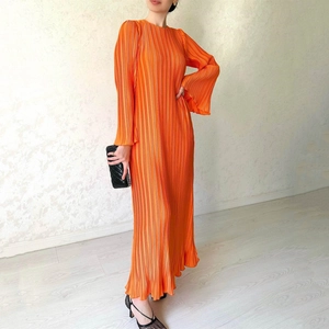 Detail of vibrant orange pleated dress featuring long bell sleeves and silky texture