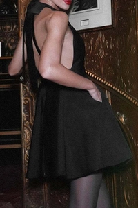 Vue détaillée du dos nu d'une robe de cocktail noire avec un élégant nœud attaché