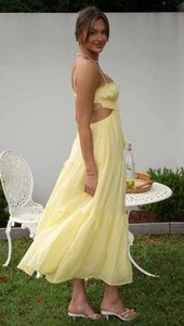 Detail of pale yellow sleeveless maxi dress featuring cut-out waist and tiered ruffle hem