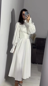 Détail de la robe longue en satin blanc perle avec manches bouffantes et volants
